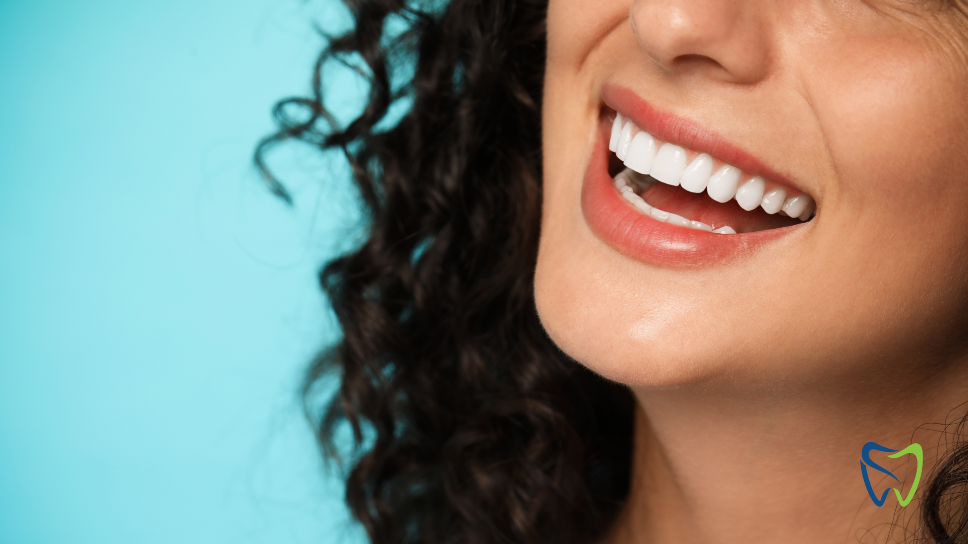 A close up of a woman 's smile with curly hair on a blue background.