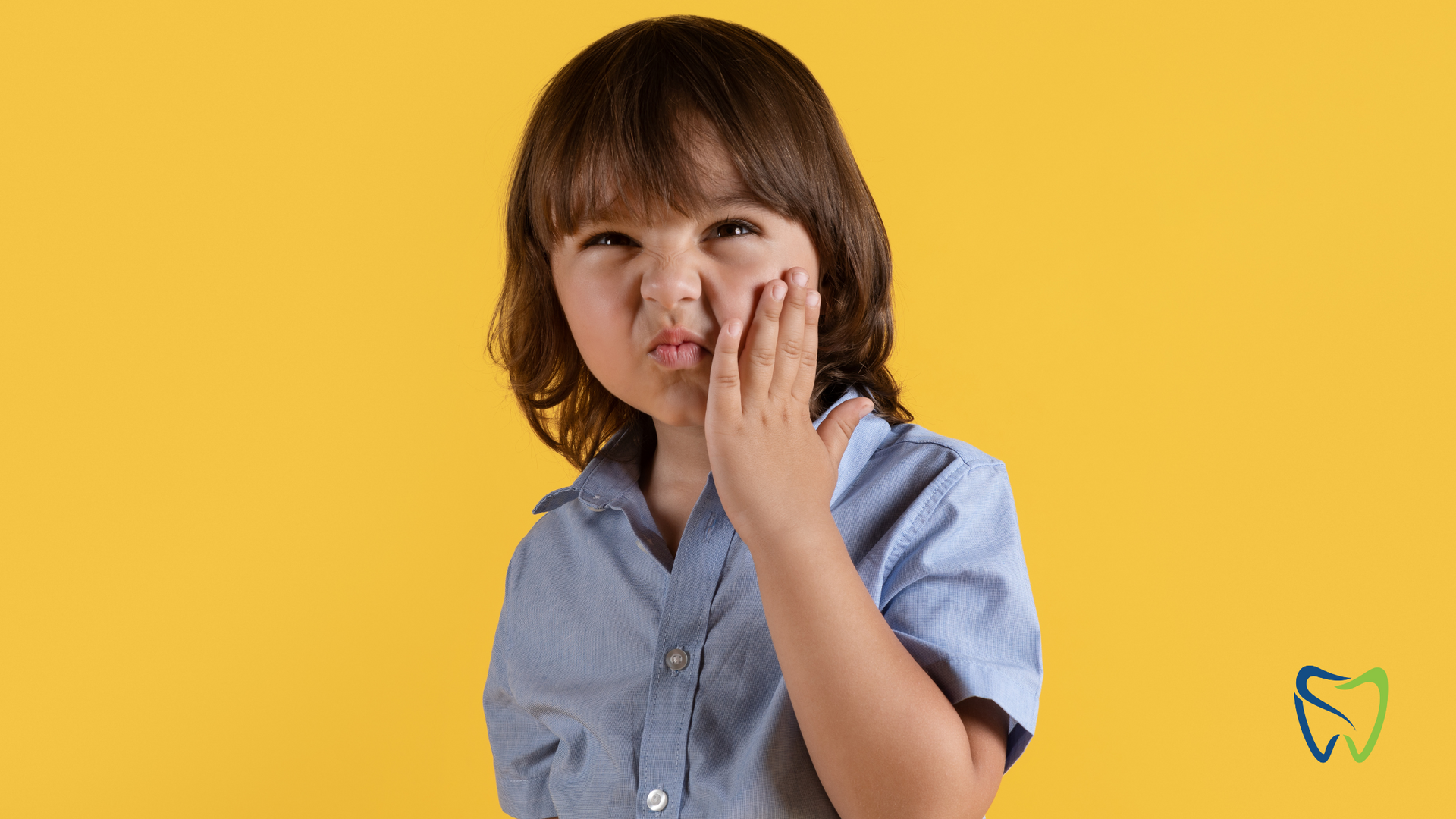 A young boy is holding his face because he has a toothache.