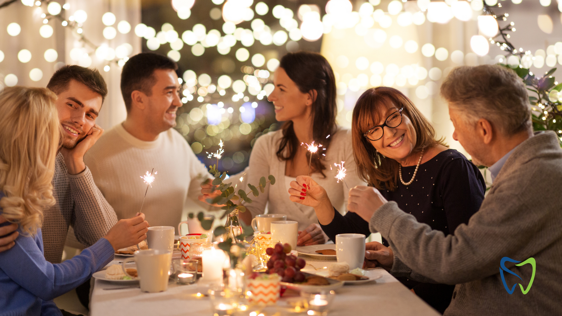 A group of people are sitting at a table holding sparklers.