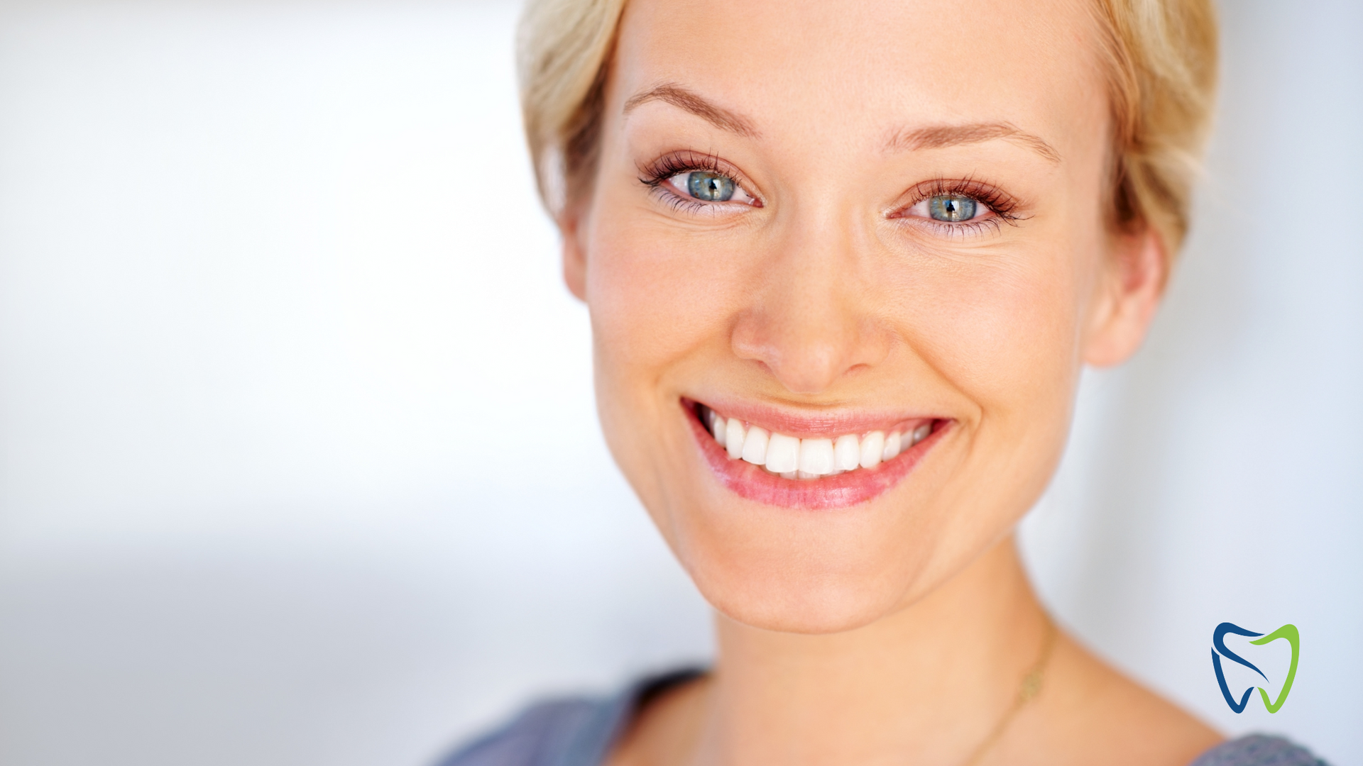 A close up of a woman smiling with a tooth in the background.