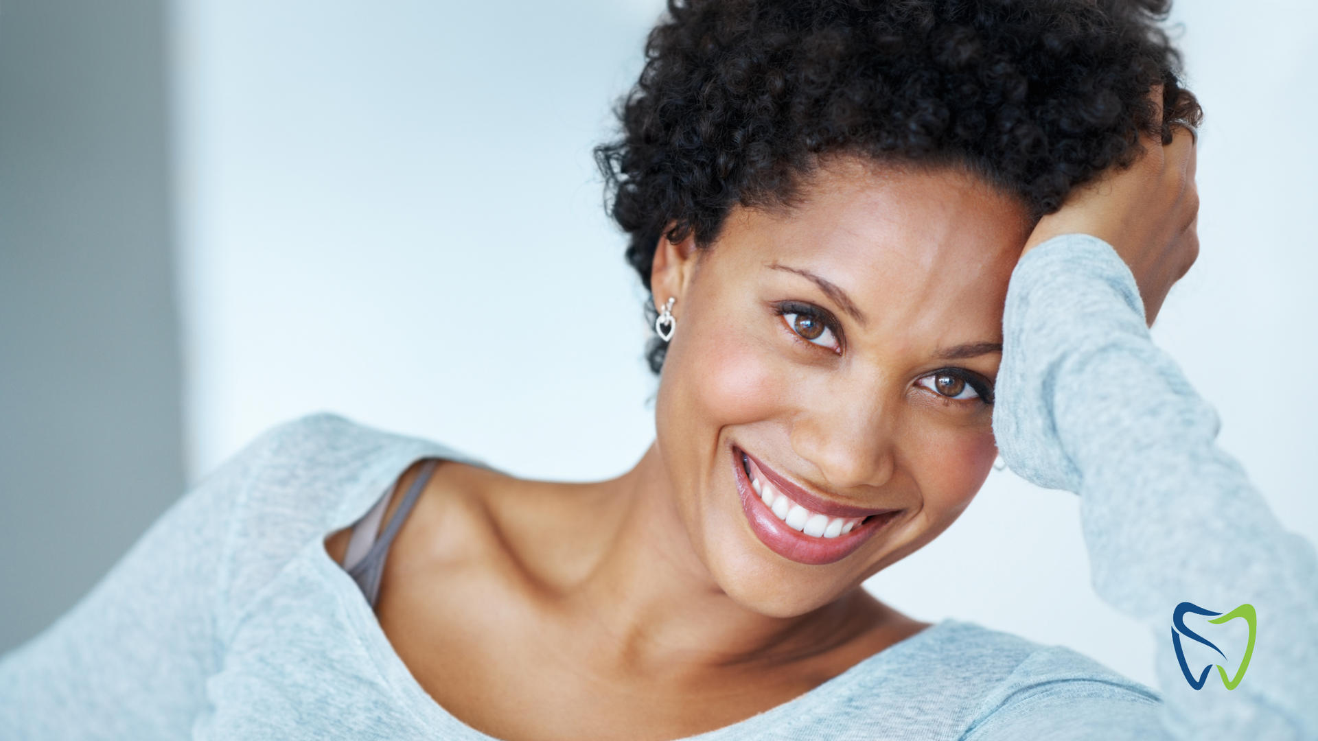 A woman is smiling with her hand in her hair.