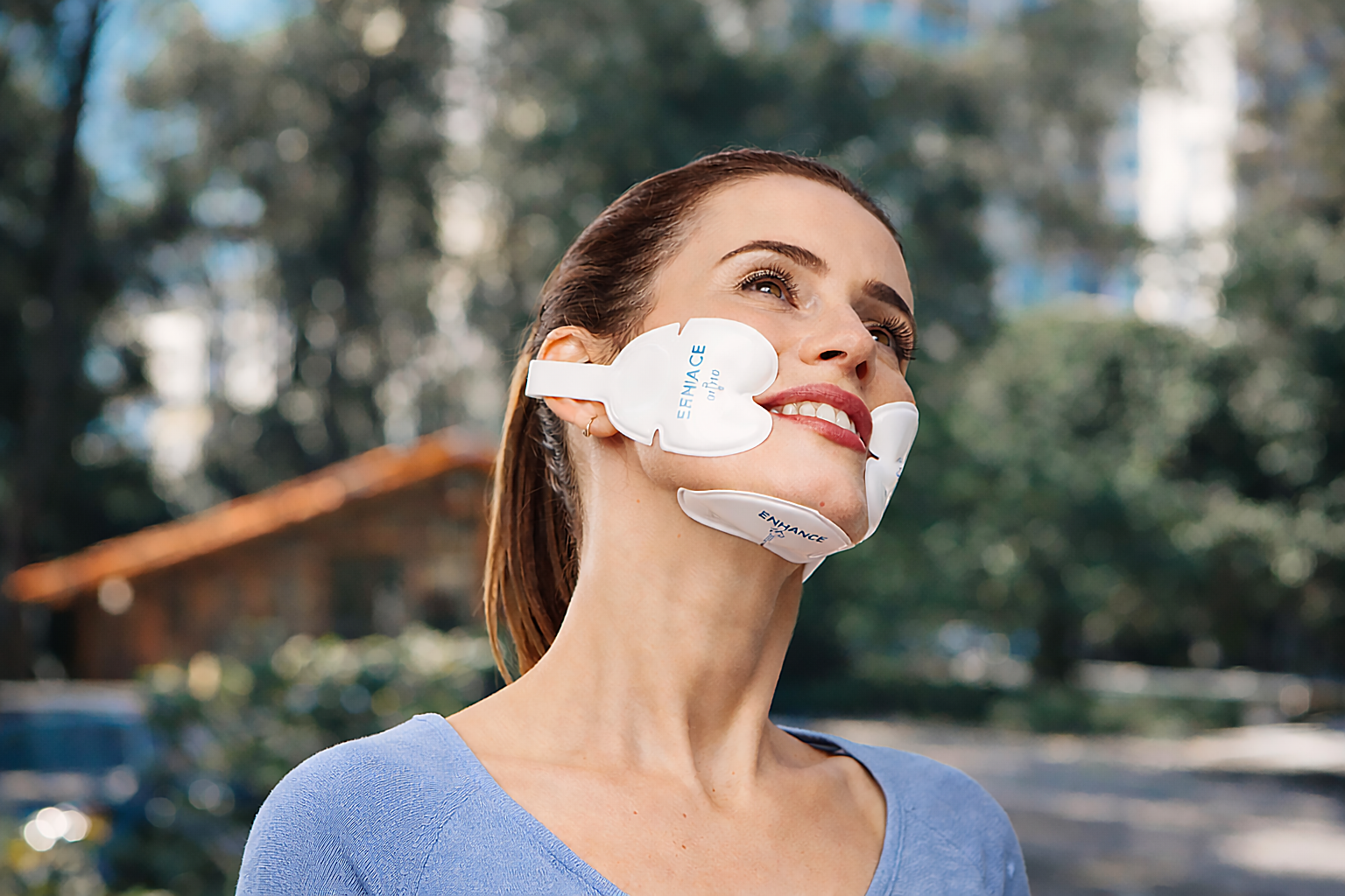 Woman wearing facial skin patches outdoors, looking upward.