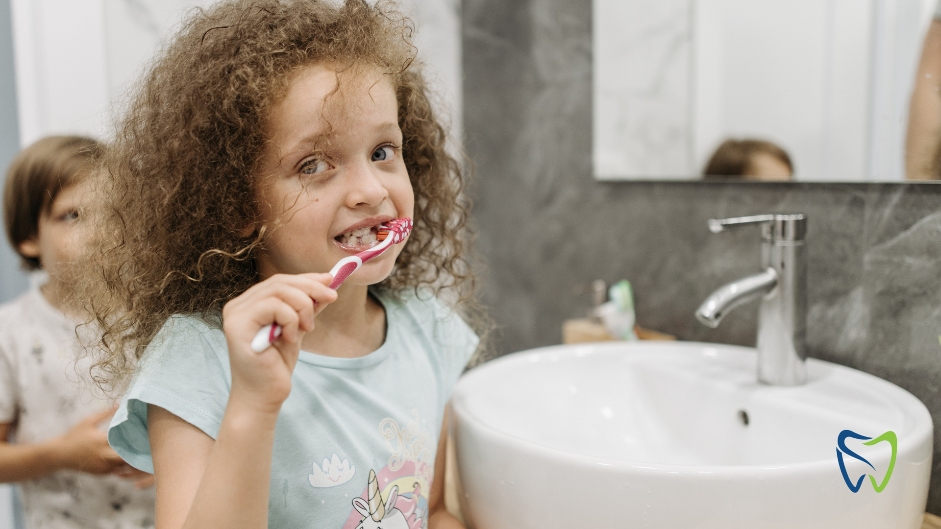 A little girl is brushing her teeth in front of a sink.