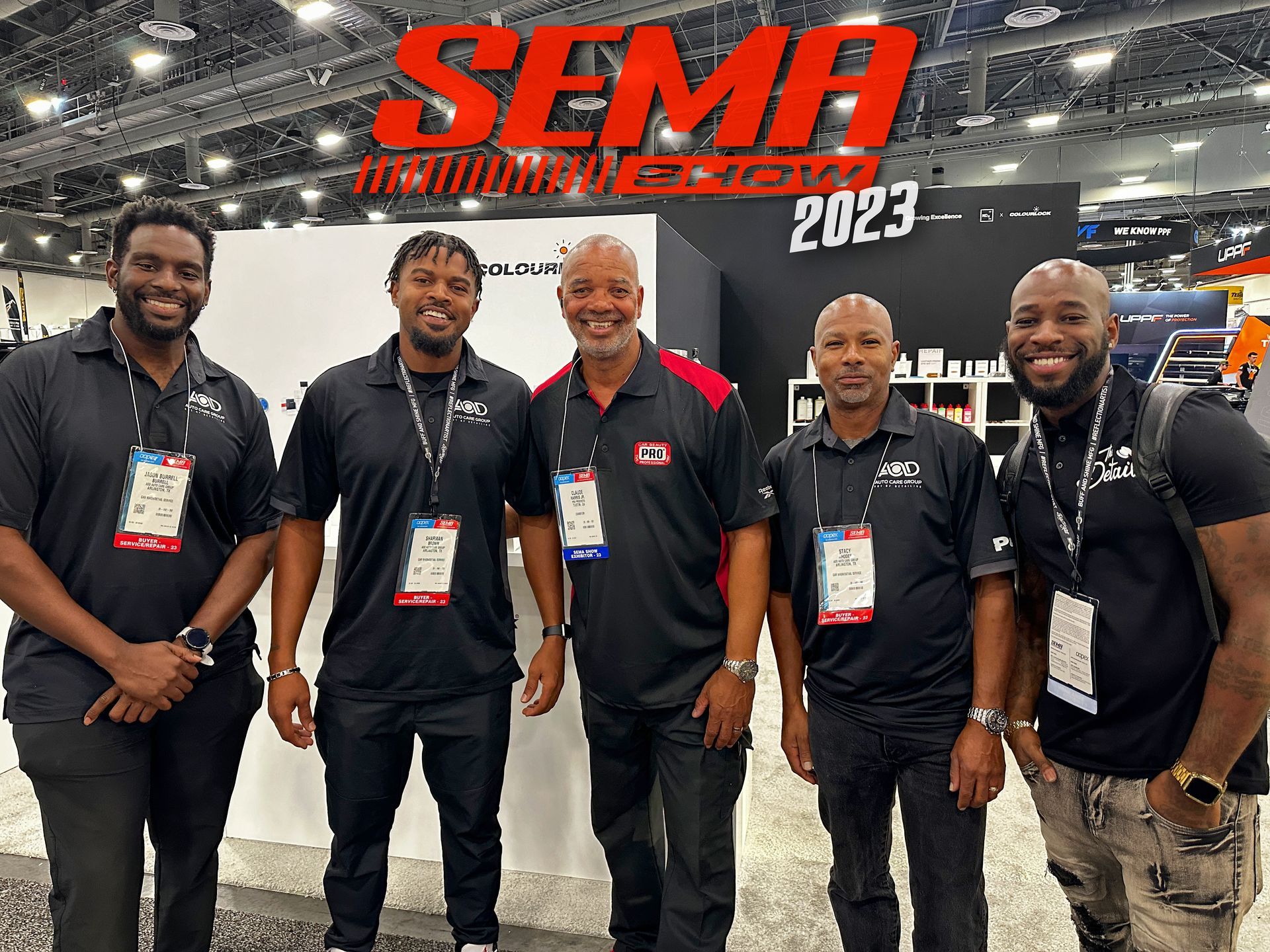 Five men posing in front of the SEMA Show 2023 sign. They are wearing black shirts and lanyards.