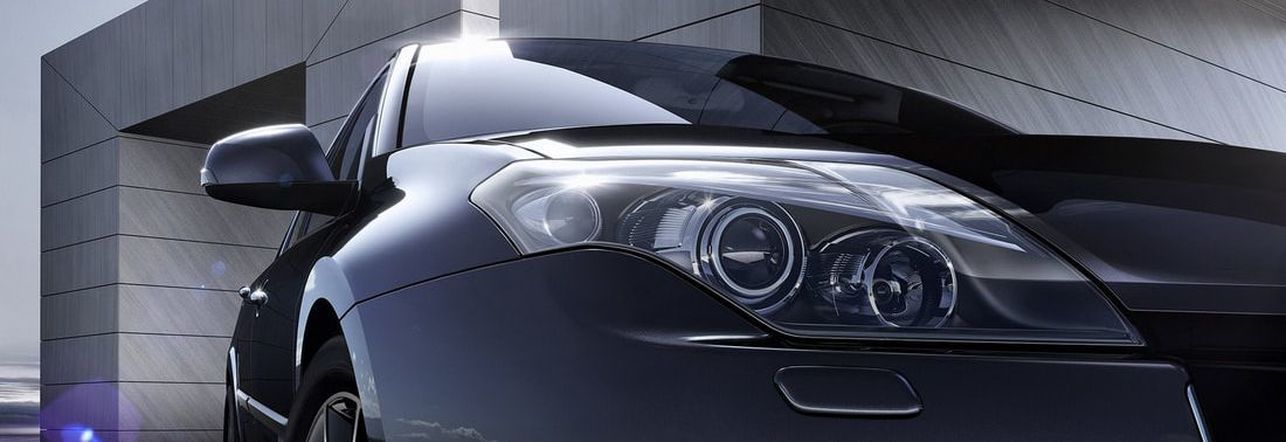 Black car parked near a modern building, headlights illuminated, front view | Good Honest Mechanic