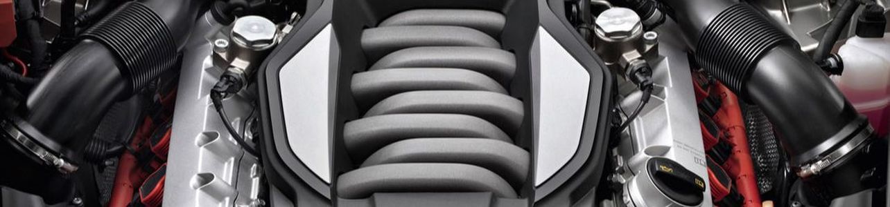 Engine compartment, close-up view of the engine, with grey coils in the center and black tubes | Good Honest Mechanic