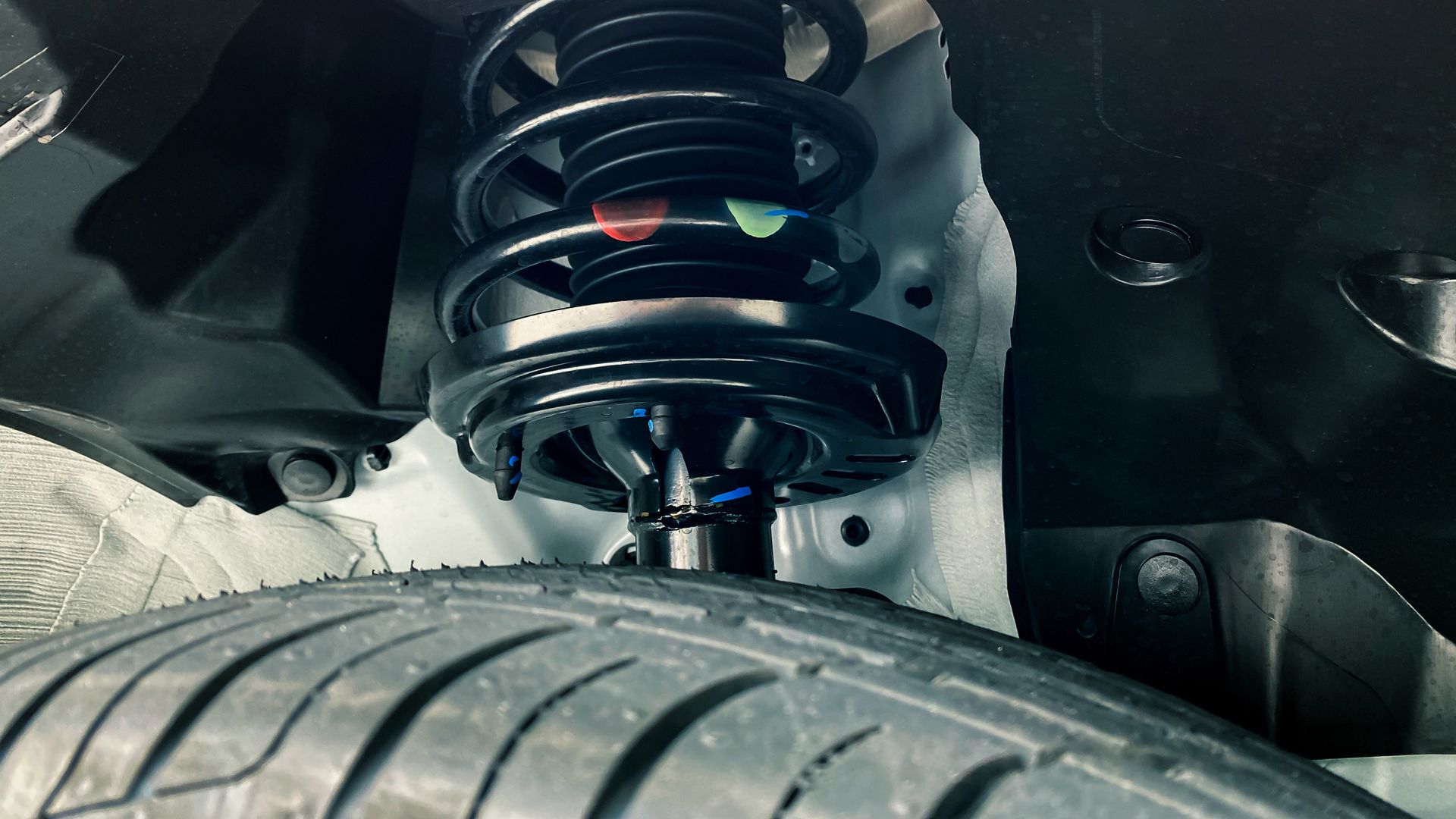 A close-up of a shock absorber and a tire on a car.