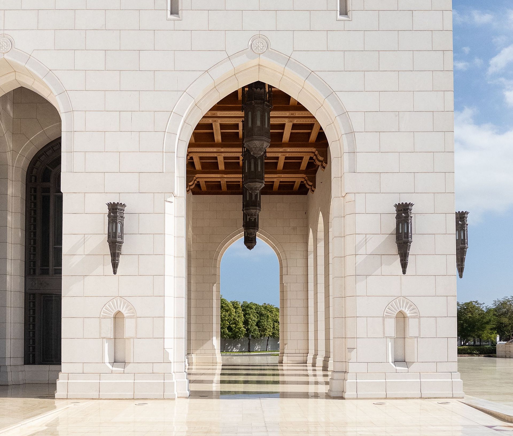White stone arched doorway with a view to trees and sky.