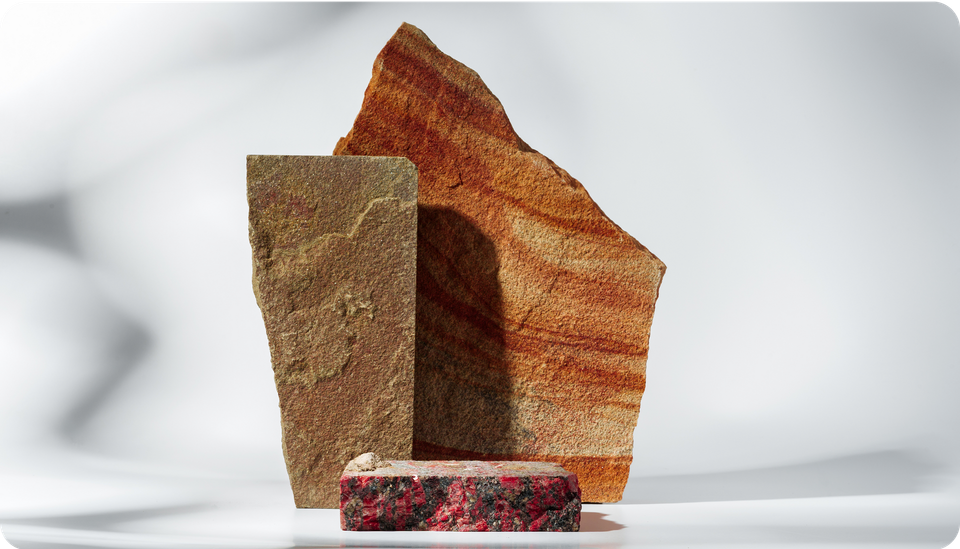 Three textured rocks: a tall brown rectangle, a layered orange triangle, and a small red rectangle.
