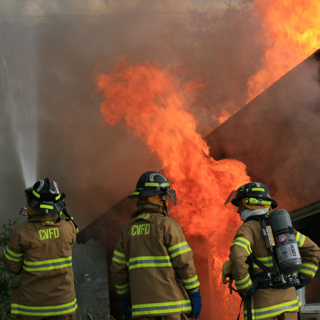 Firefighters battling a house fire, spraying water at flames.