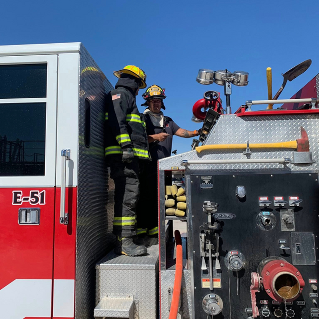 Firefighters at a fire truck, examining equipment. 