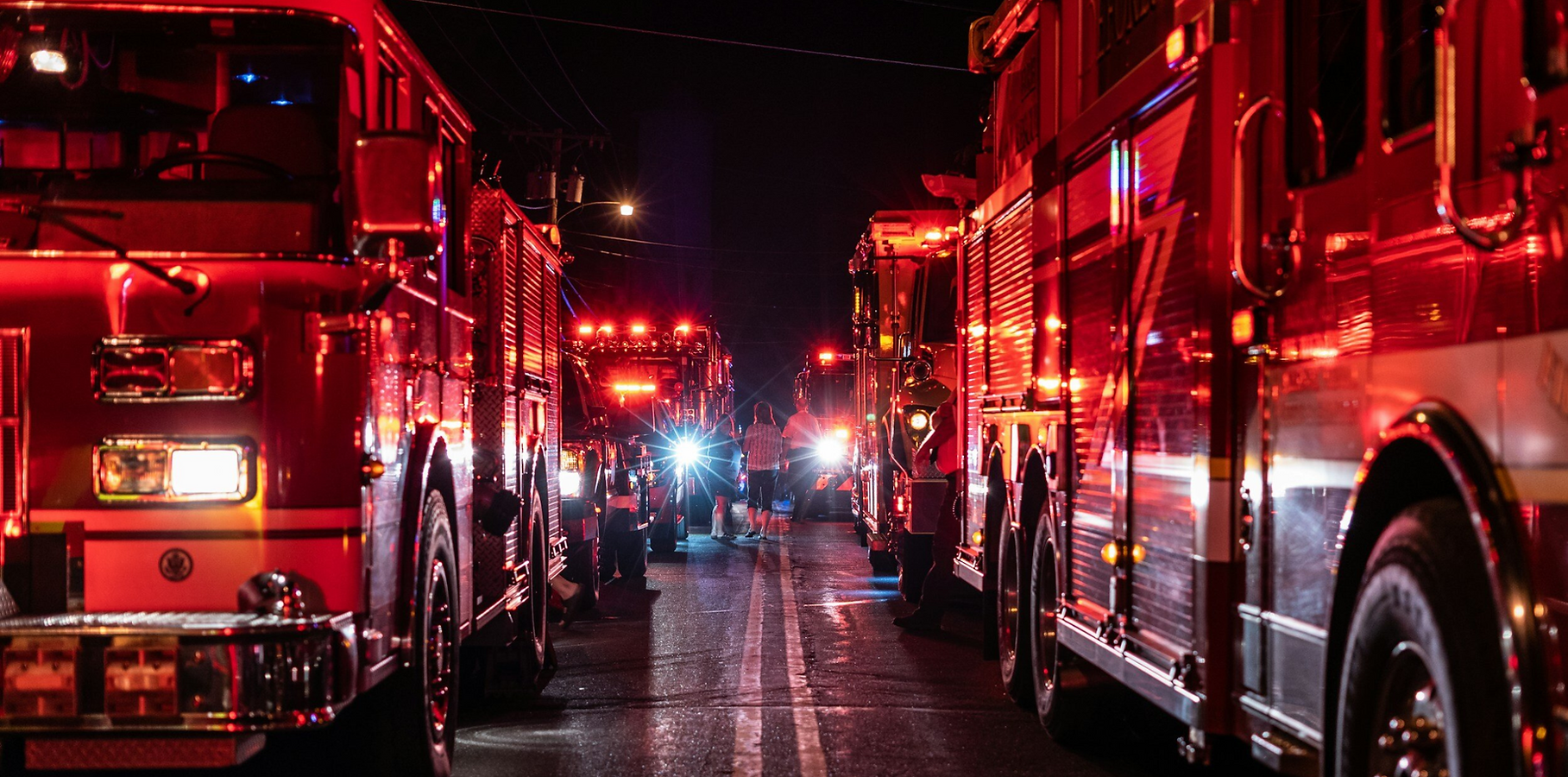 Fire trucks with flashing lights at night.