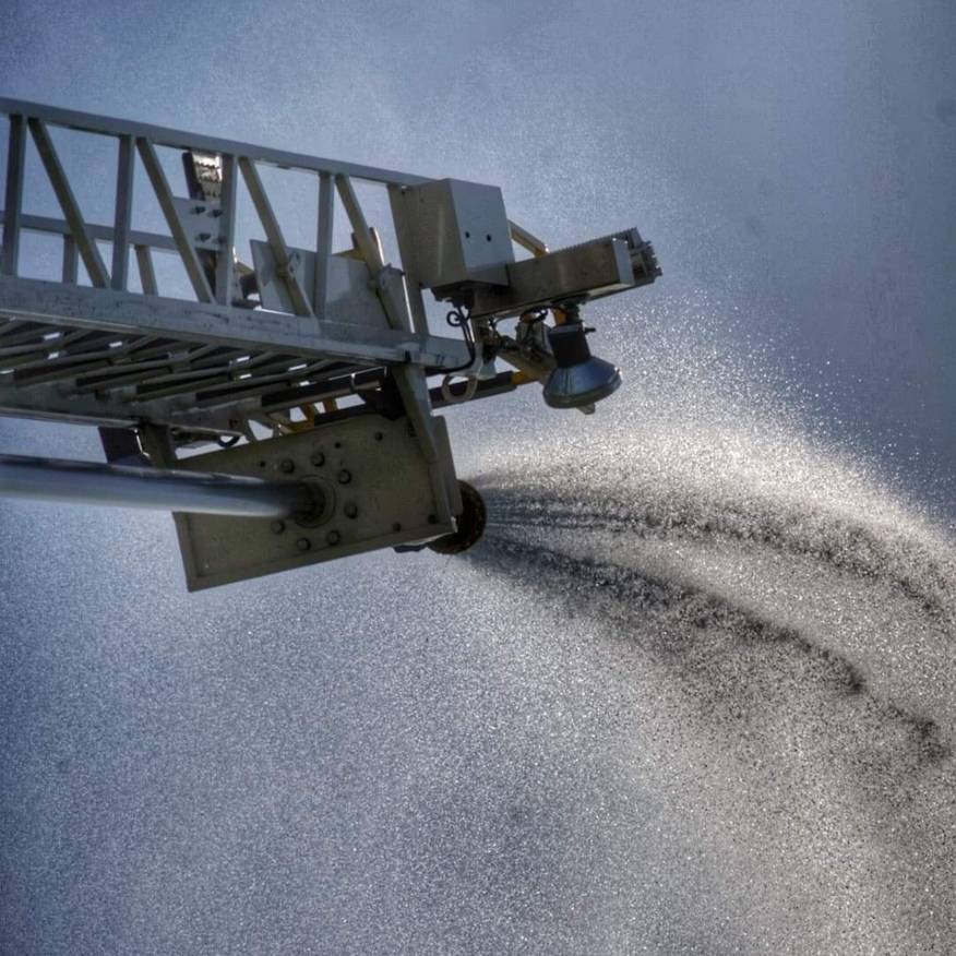 Fire truck ladder spraying water into the air.