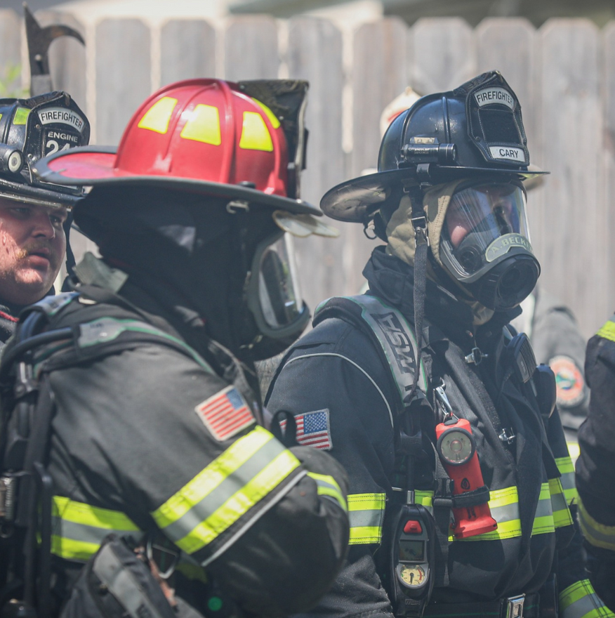 Firefighters in protective gear, wearing masks and helmets at a scene.