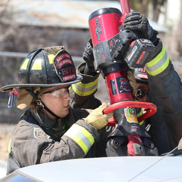 Firefighters using hydraulic rescue tool to cut a vehicle roof.