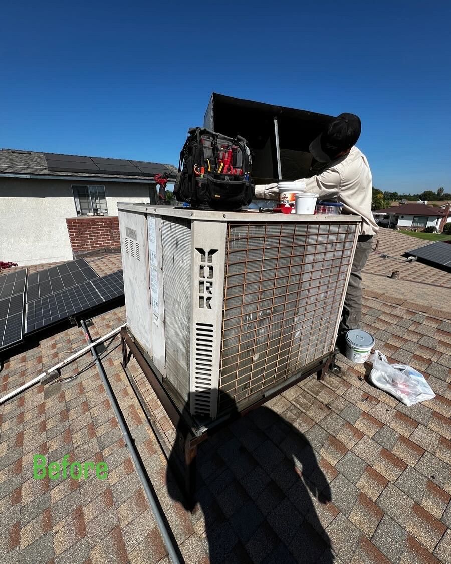 A man is working on an air conditioner on top of a roof.