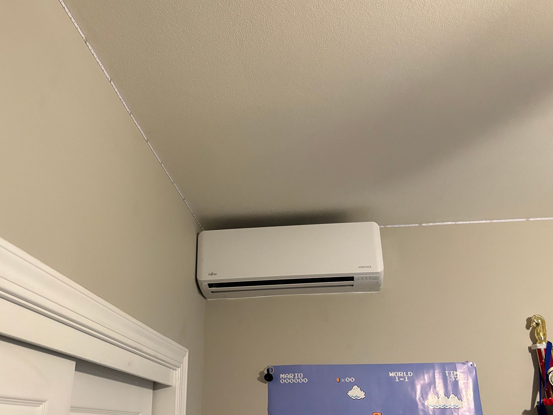 A white air conditioner is hanging from the ceiling in a room.