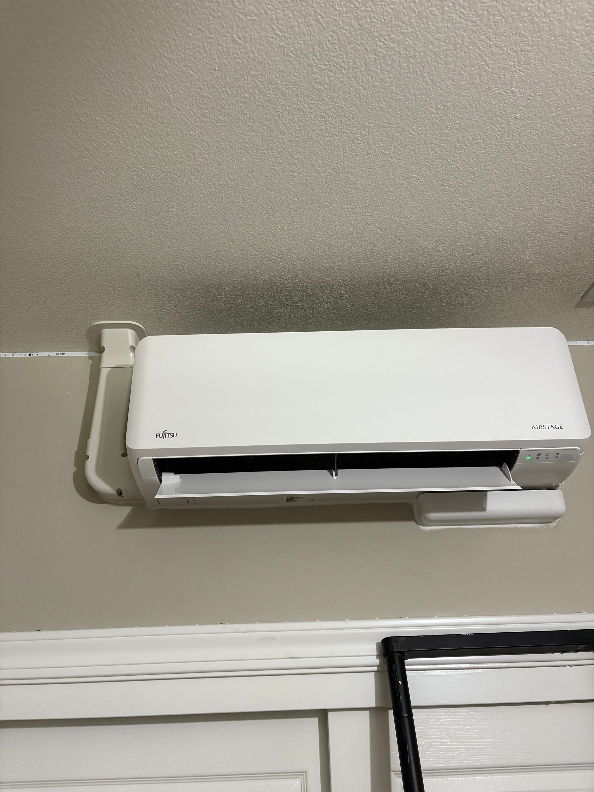 A white air conditioner is hanging on a wall next to a window.