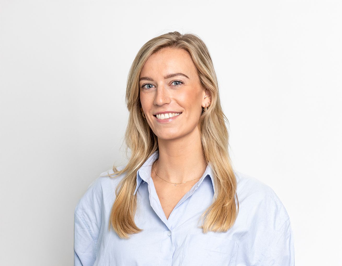 Een vrouw in een blauw shirt lacht naar de camera.
