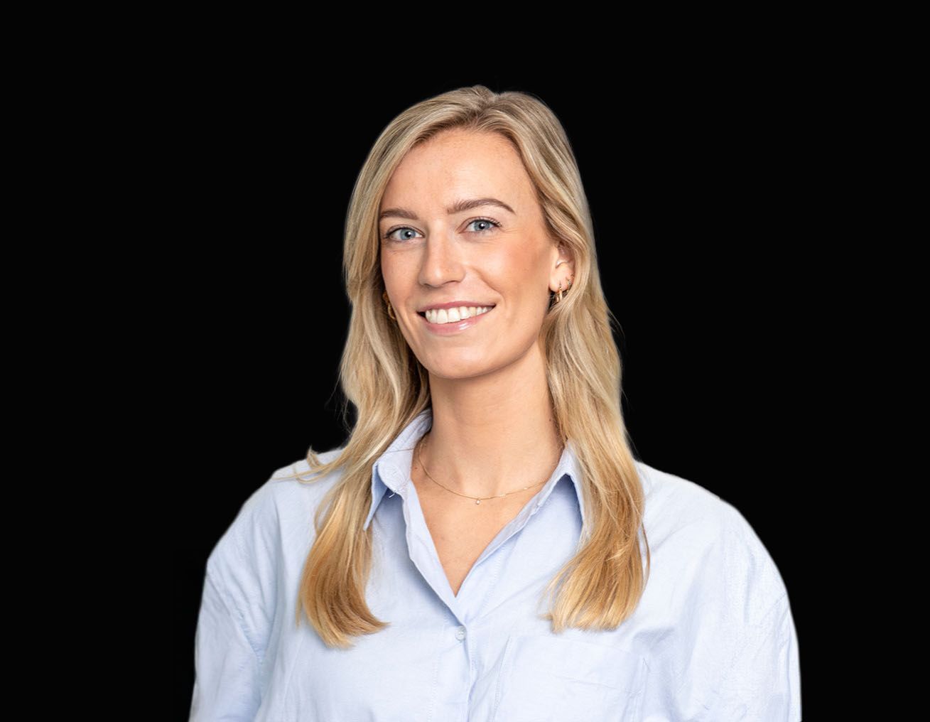 Een vrouw in een blauw shirt lacht naar de camera.