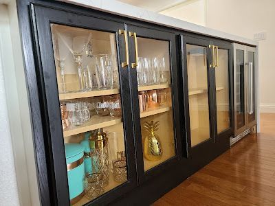 A kitchen cabinet with glass doors and shelves filled with glasses.