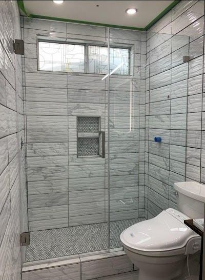A bathroom with a toilet and a shower with a glass door.