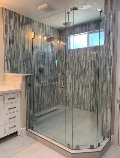 A bathroom with a walk in shower with a glass door.