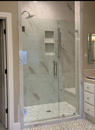 A bathroom with a walk in shower with a glass door.