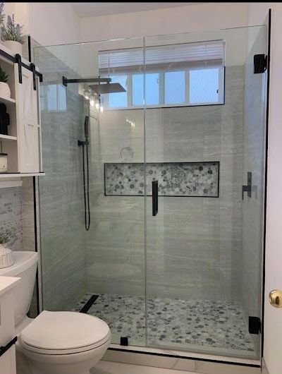 A bathroom with a toilet and a shower with a glass door.