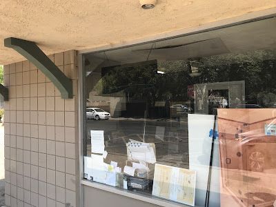A store front with a large window and a reflection of a car in the window.