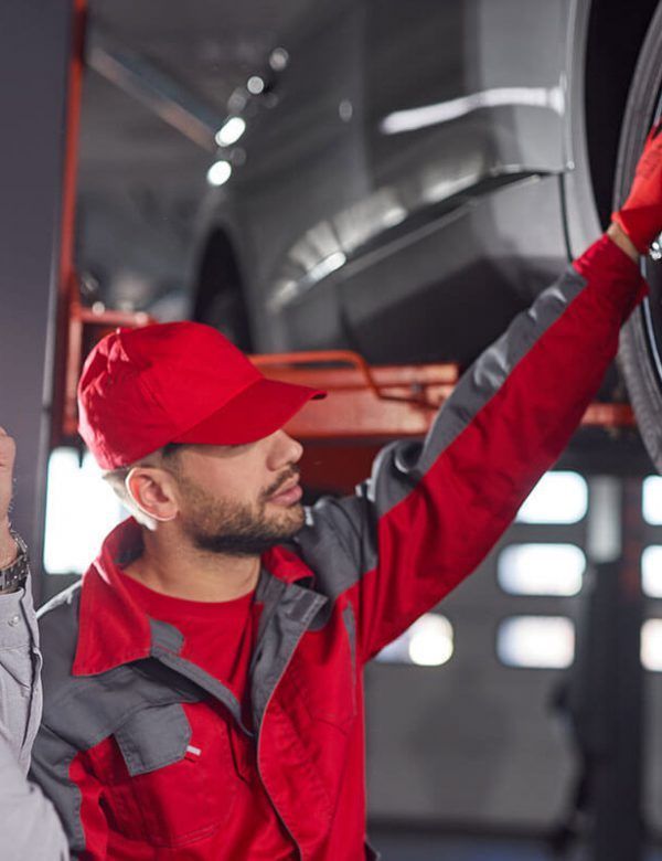 A man in a red hat is working on a car tire.