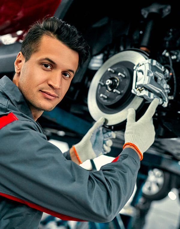 A man is fixing a brake on a car in a garage.
