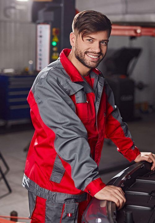 A man is standing next to a car in a garage.
