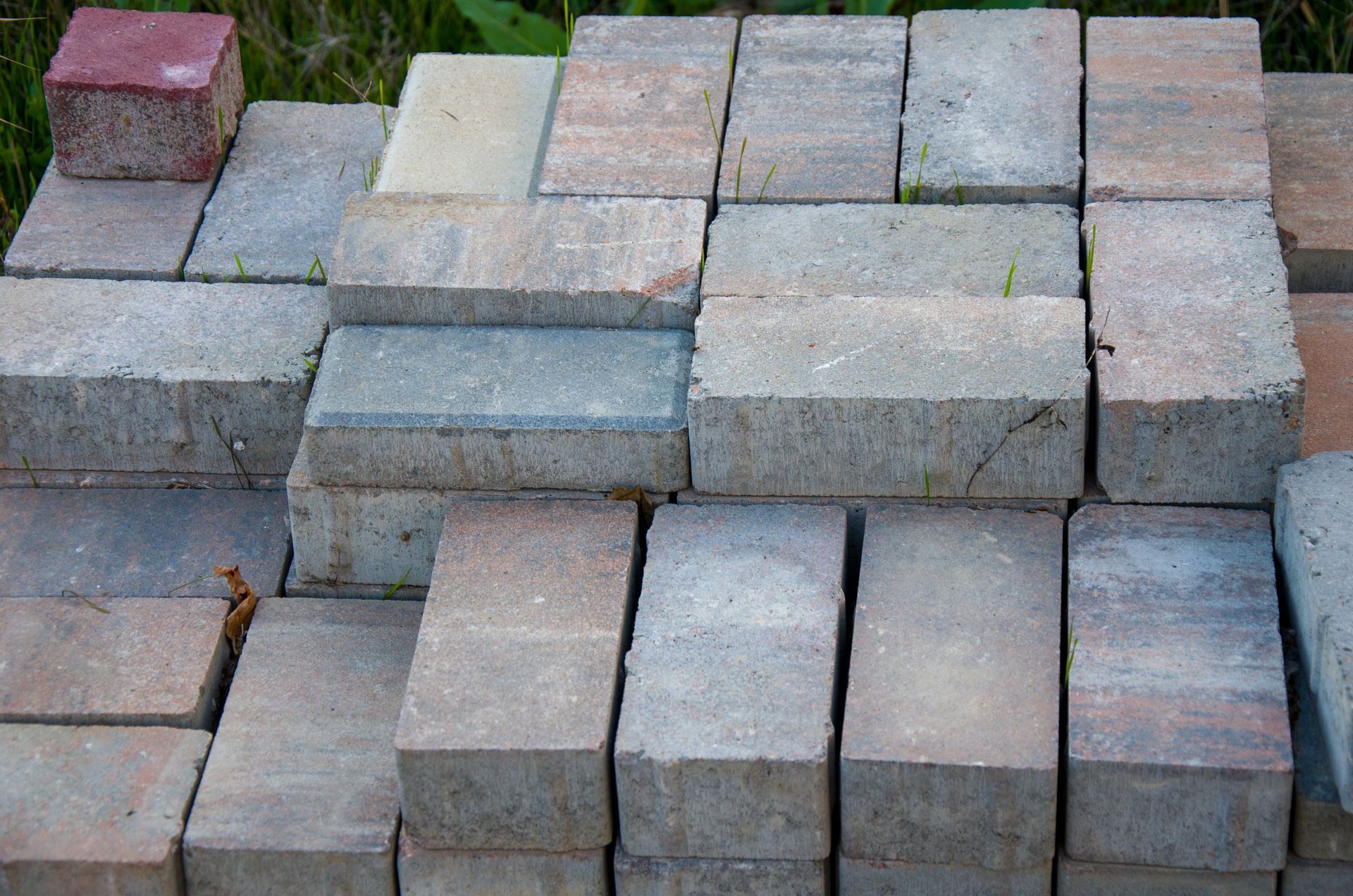 Stack of rectangular gray and tan concrete bricks, with a single red brick on top.