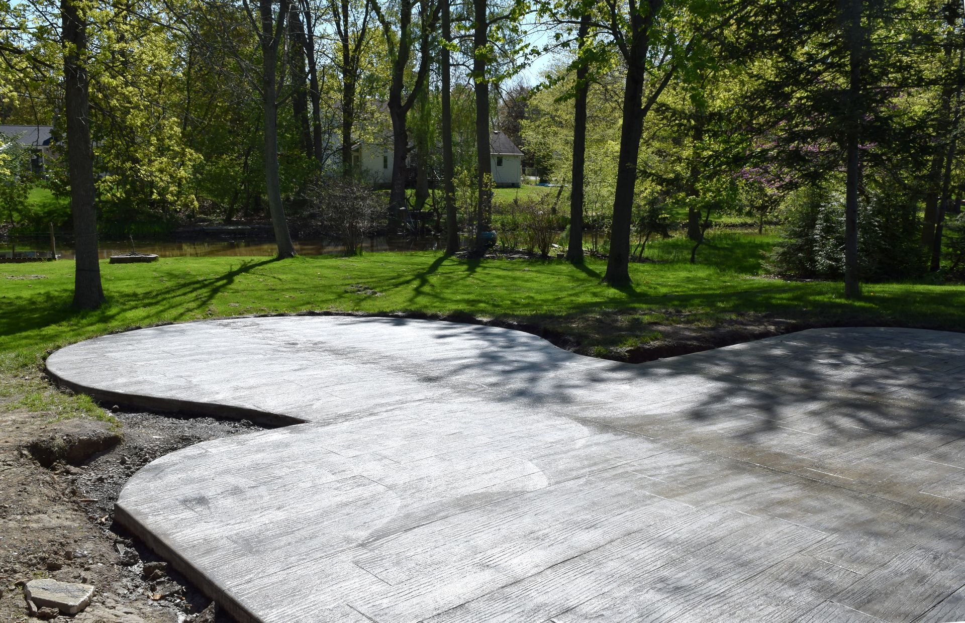 Curved concrete walkway in a sunny park with trees and green grass