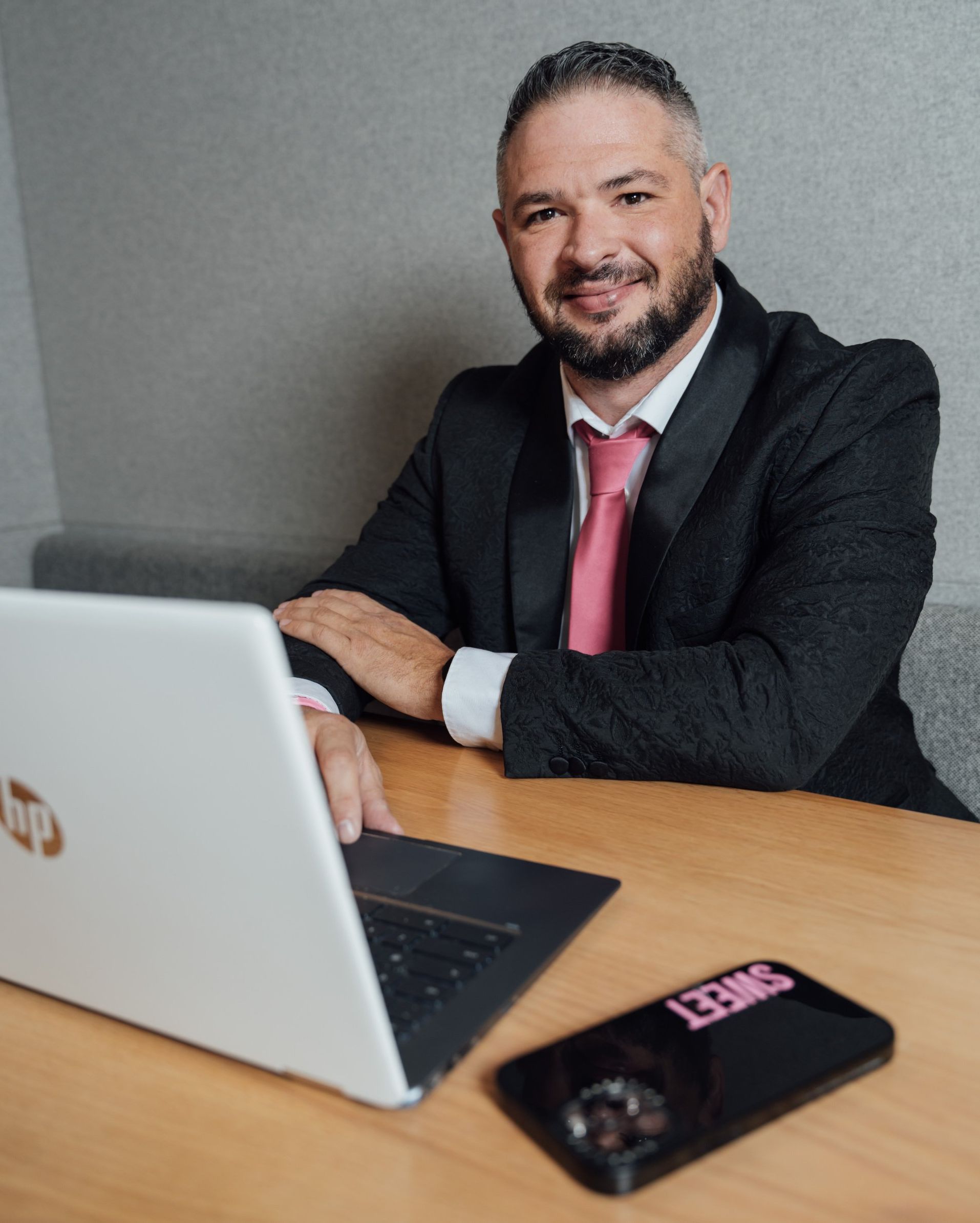 A man in a suit and tie is sitting at a table with a laptop.