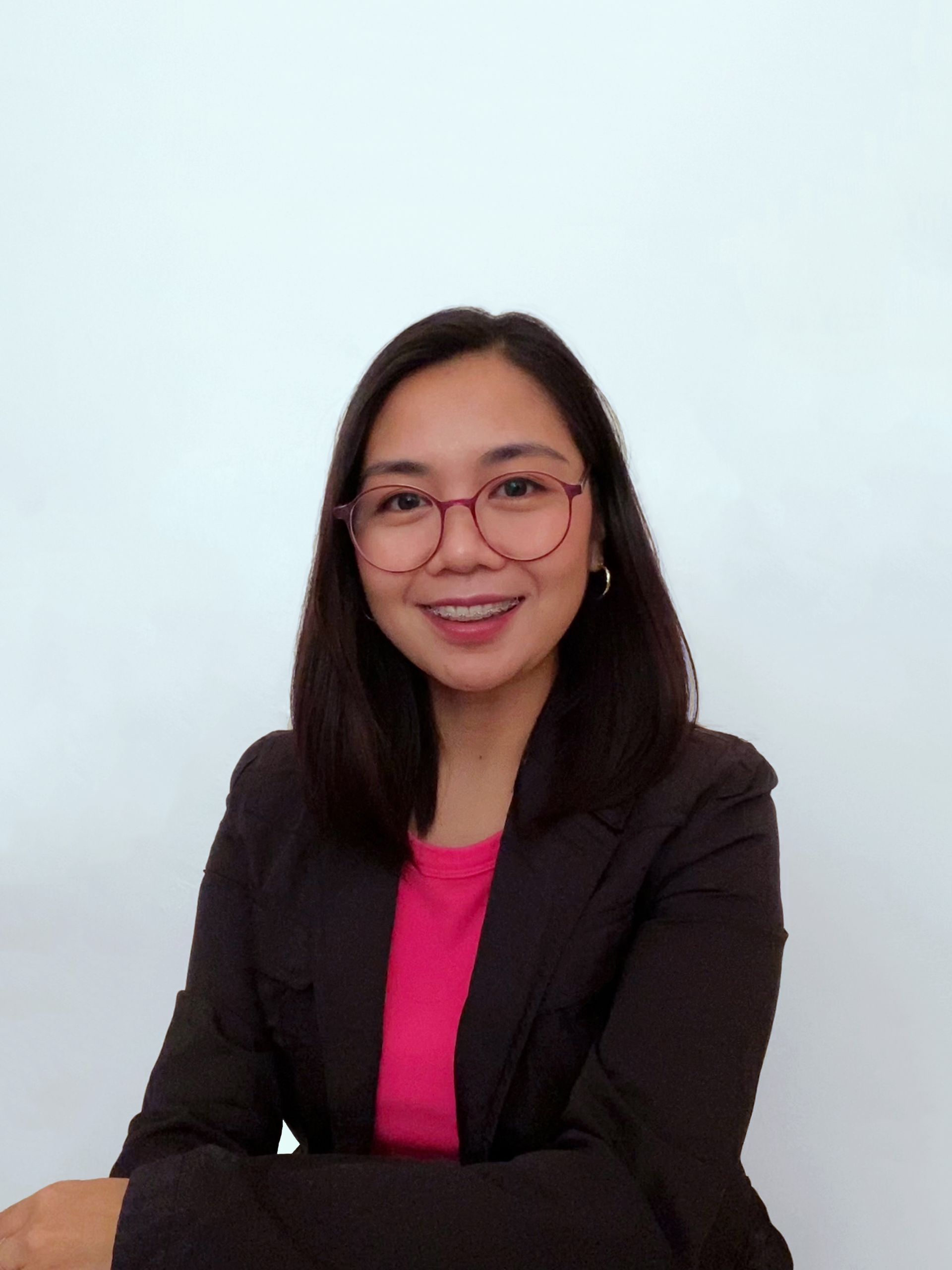 A woman wearing glasses and a black jacket is smiling for the camera