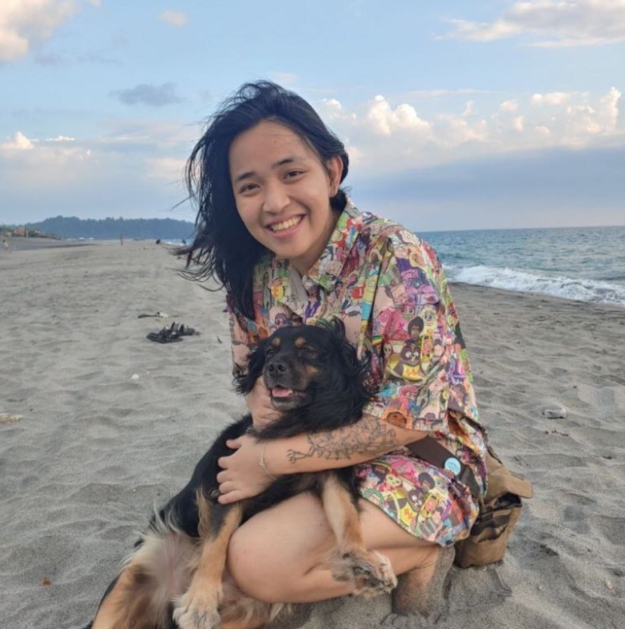 a woman is kneeling down on the beach holding a dog