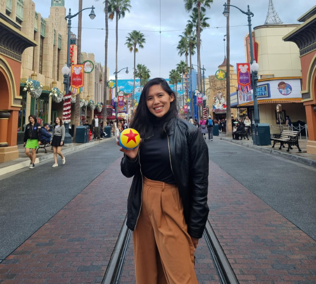 A woman in a black jacket is holding a toy story ball