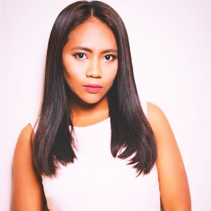 Woman with long, dark hair in a white top, looking forward with a neutral expression.