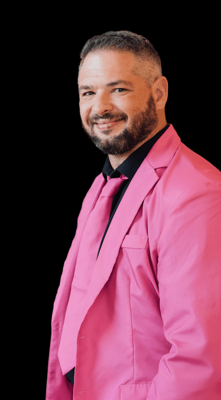 a man wearing a pink suit and tie with his hands in his pockets