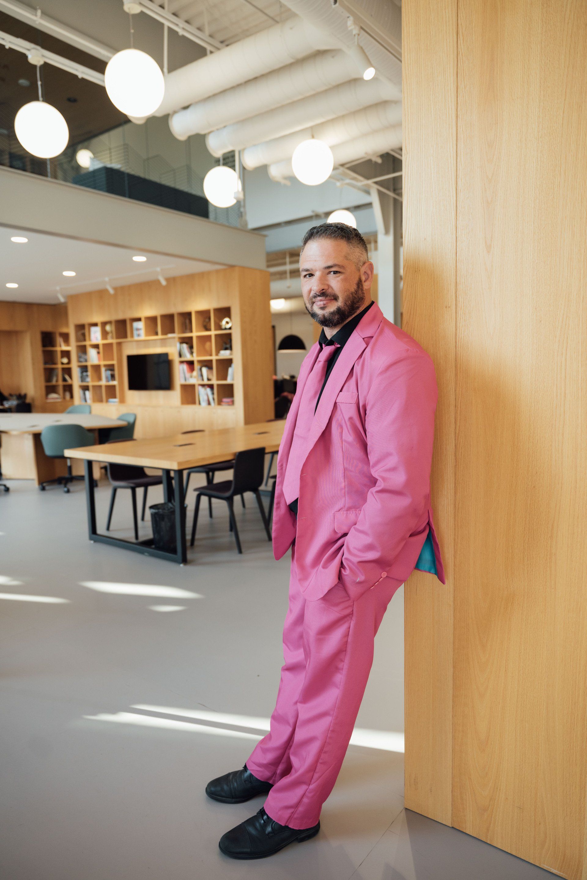 a man in a pink suit is leaning against a wall .