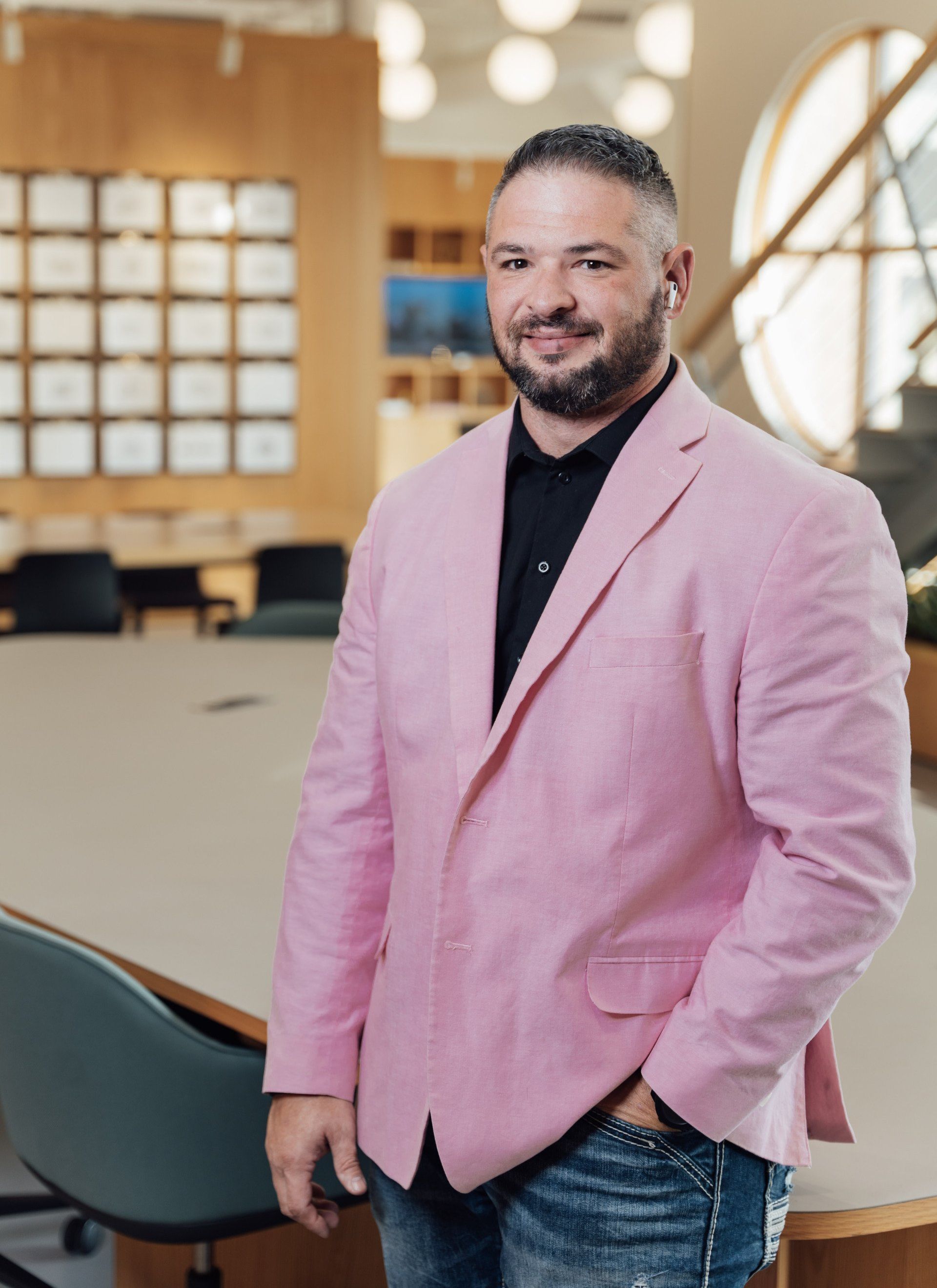 a man in a pink jacket is standing in front of a conference table .