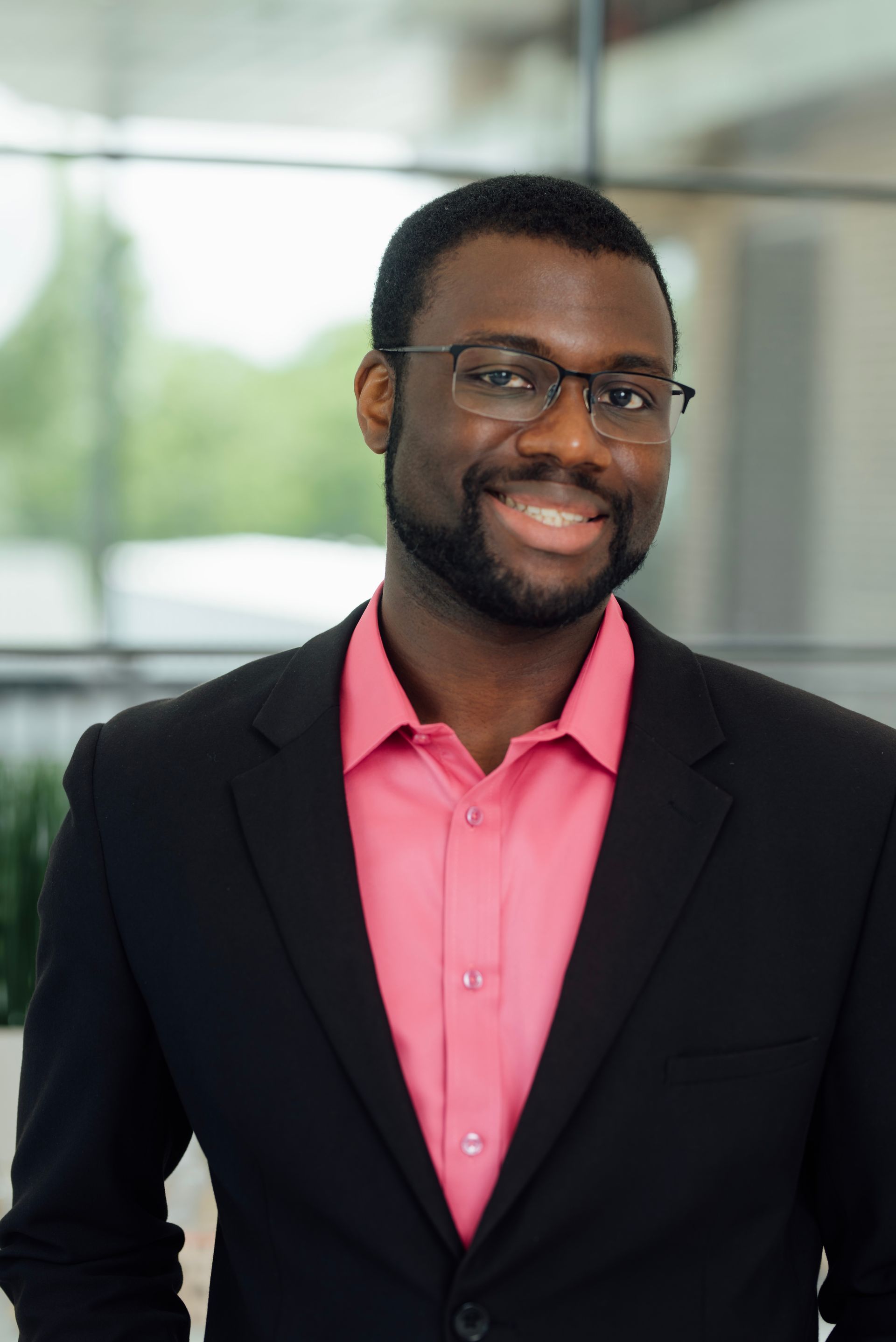 A man in a suit and pink shirt is smiling for the camera.