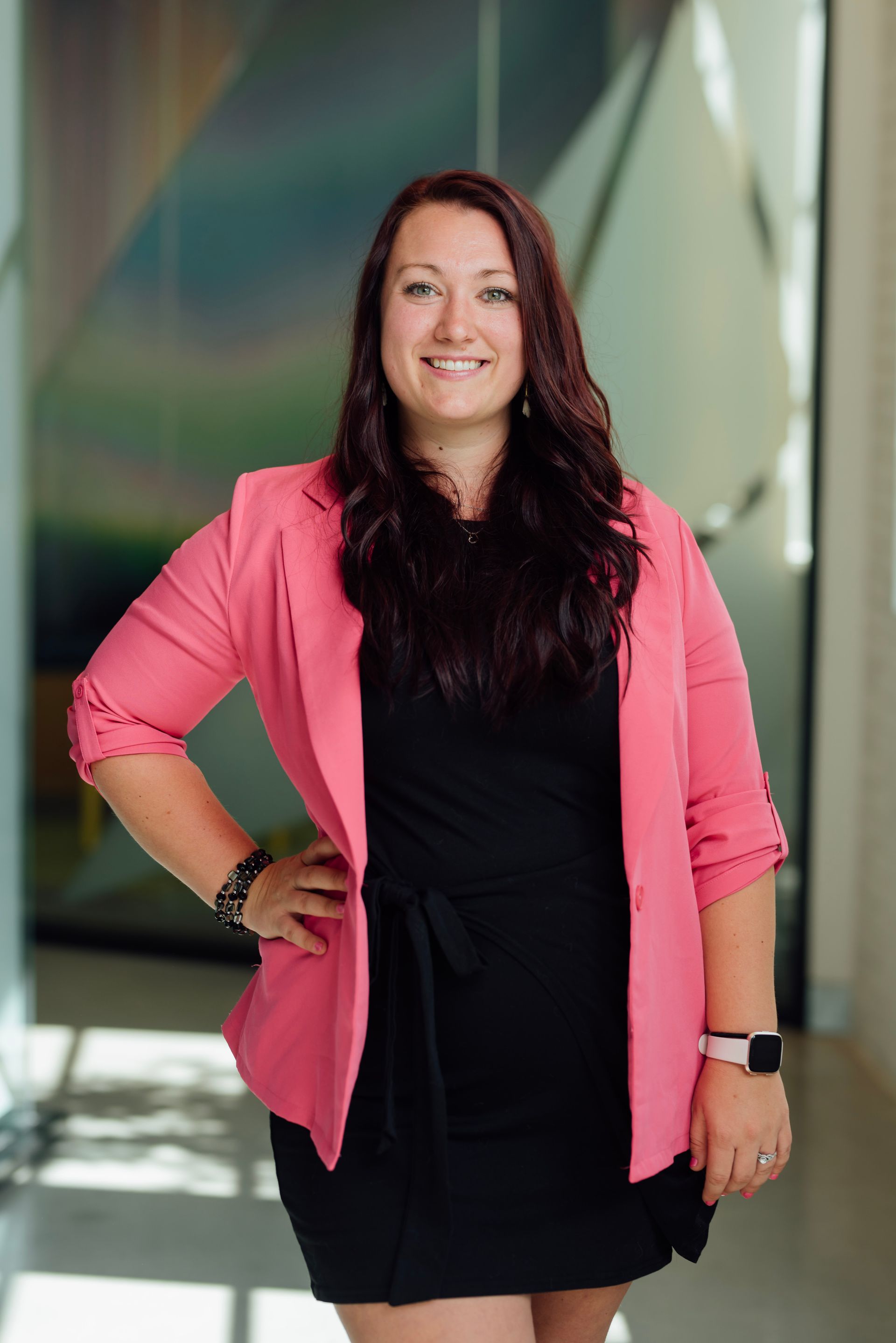A woman in a pink jacket is standing in a kitchen holding a cup of coffee.