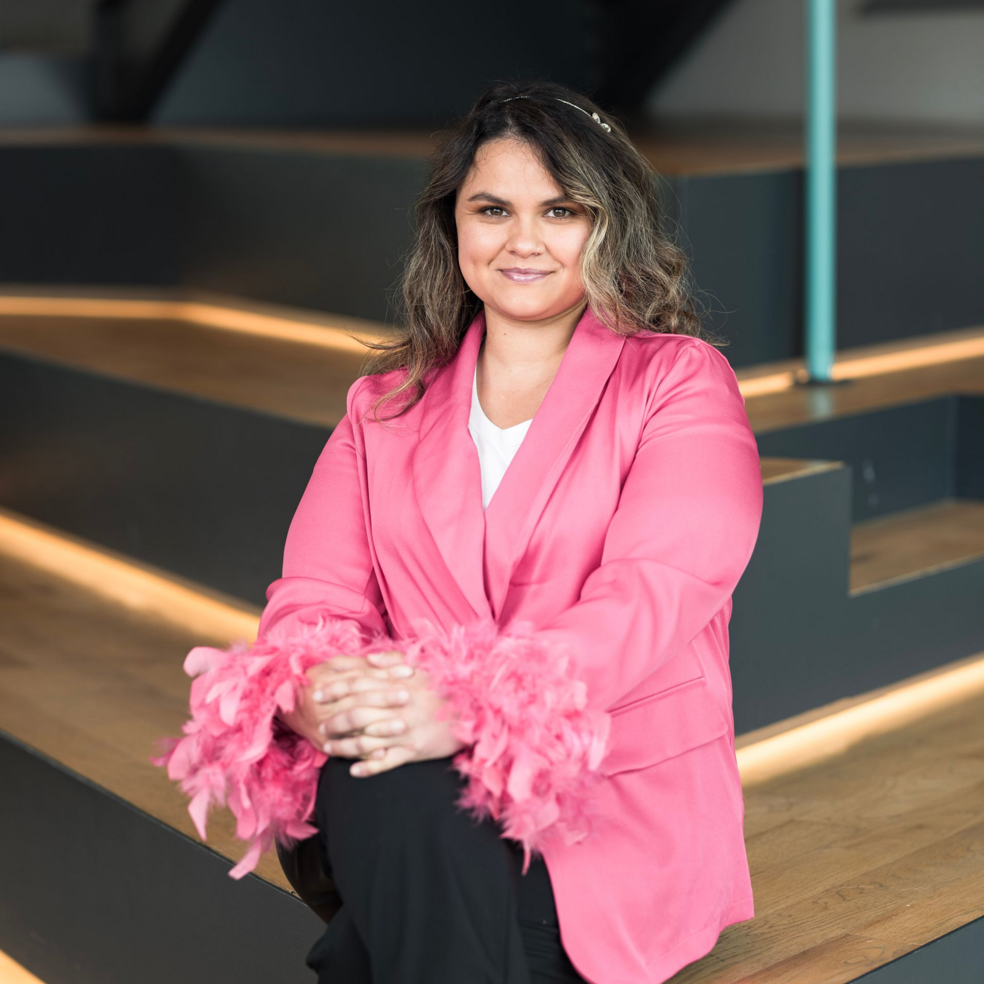 A woman in a pink jacket and pink shoes is sitting on a set of stairs.