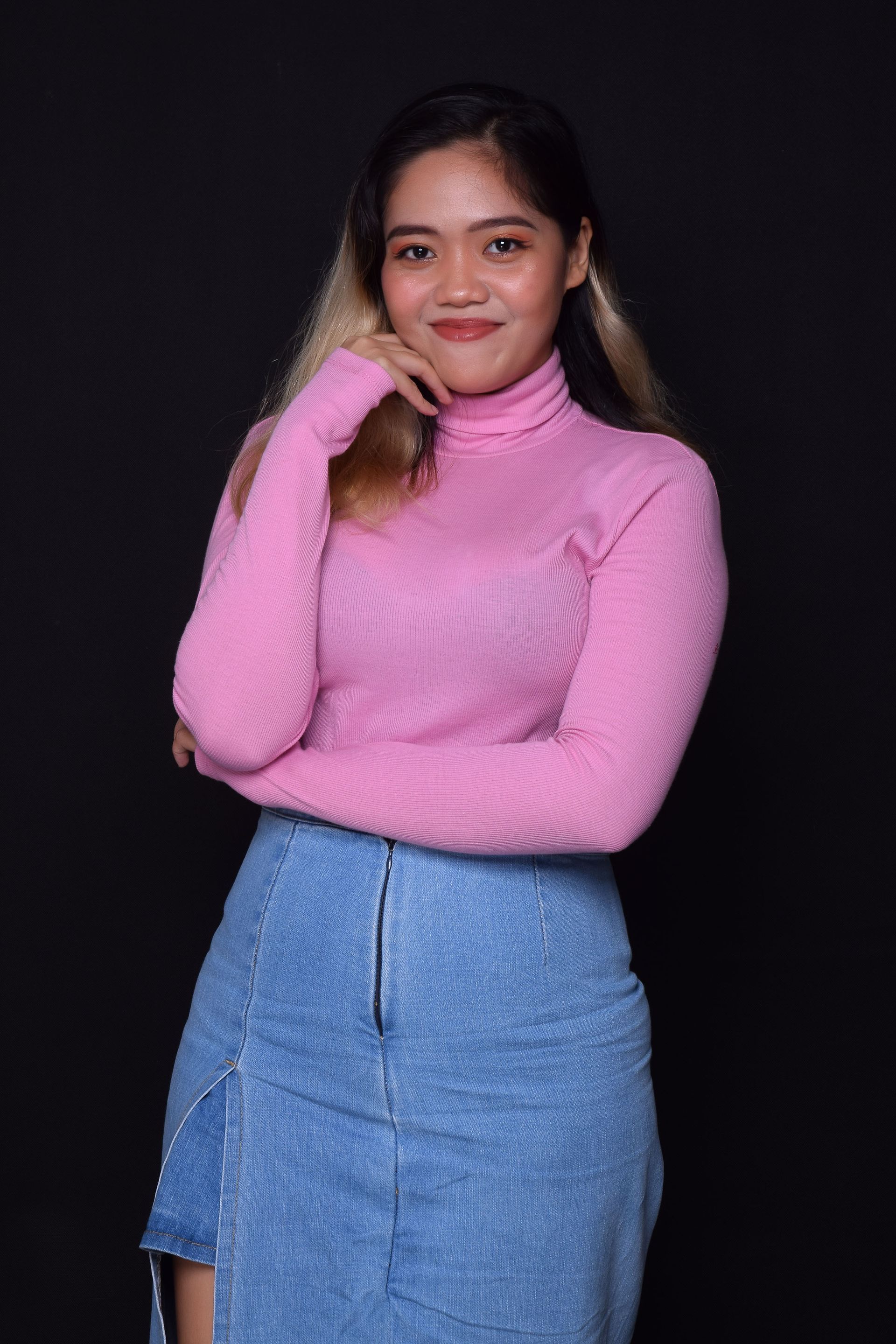the woman is wearing a pink turtleneck and a blue denim skirt .