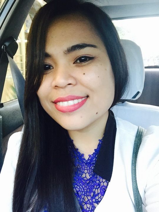A woman is smiling while sitting in the back seat of a car