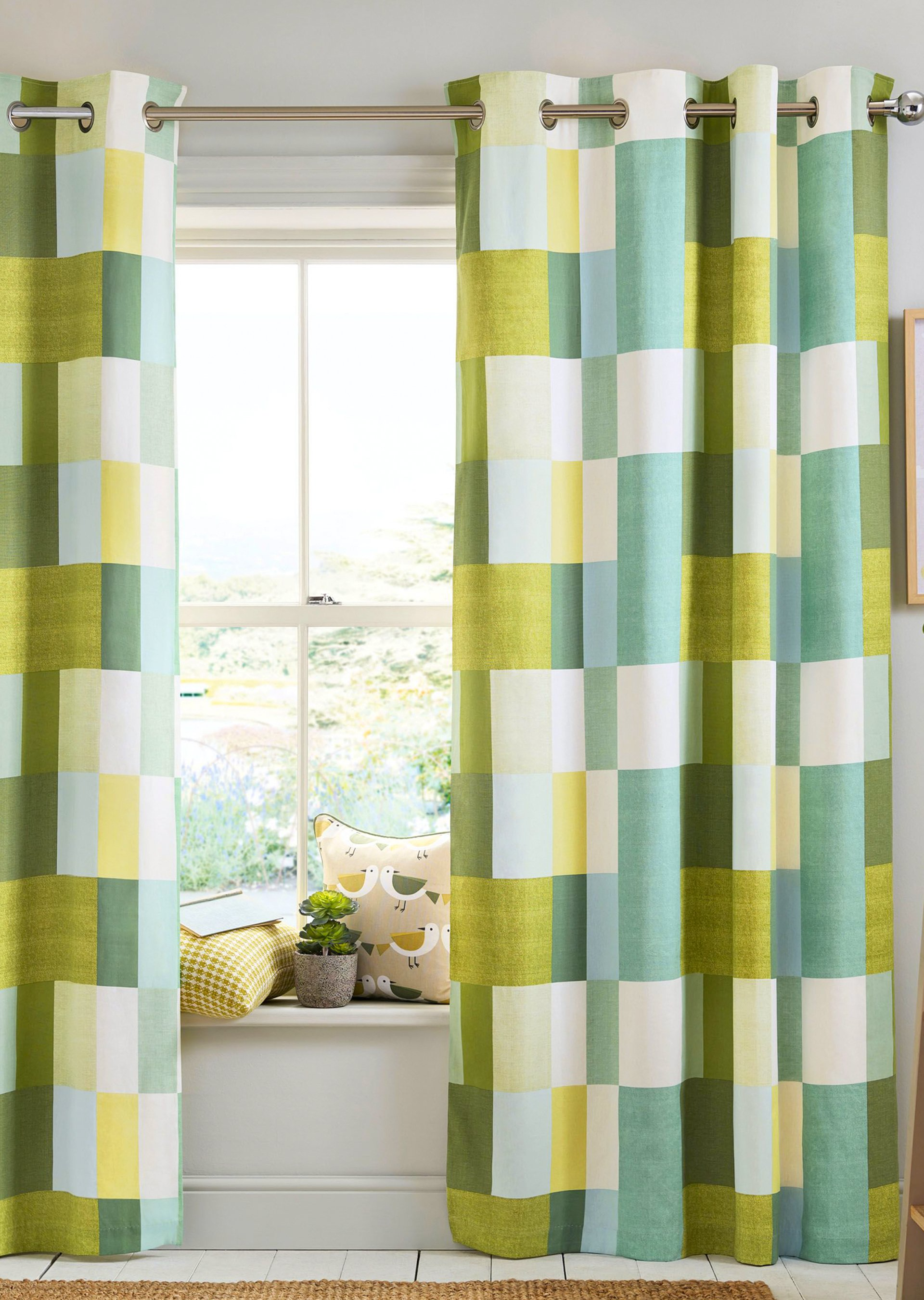 A pair of green and yellow curtains are hanging on a window.
