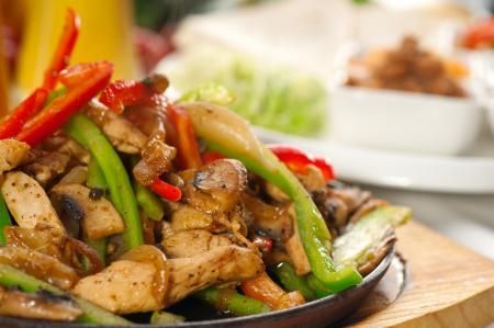 Sizzling chicken fajitas with colorful bell peppers and mushrooms served on a hot cast iron skillet.